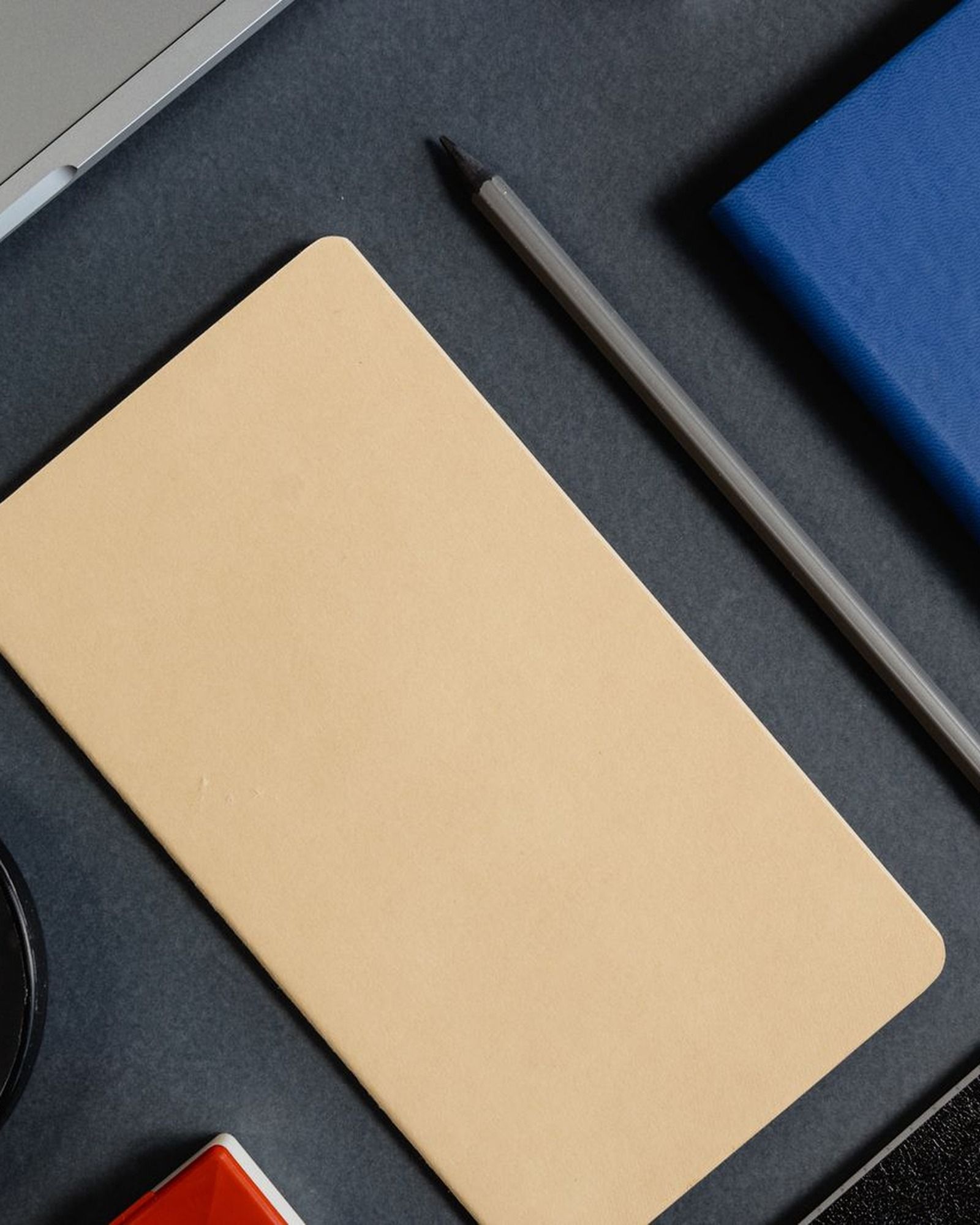 A tidy desk with a notebook, a blue planner, and a pencil laid out ready to map out a plan