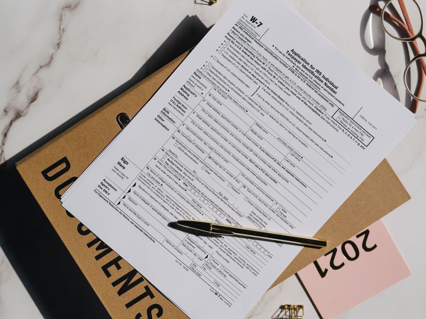 An application form and a pen resting on a documents folder, viewed from above, ready to be filled out